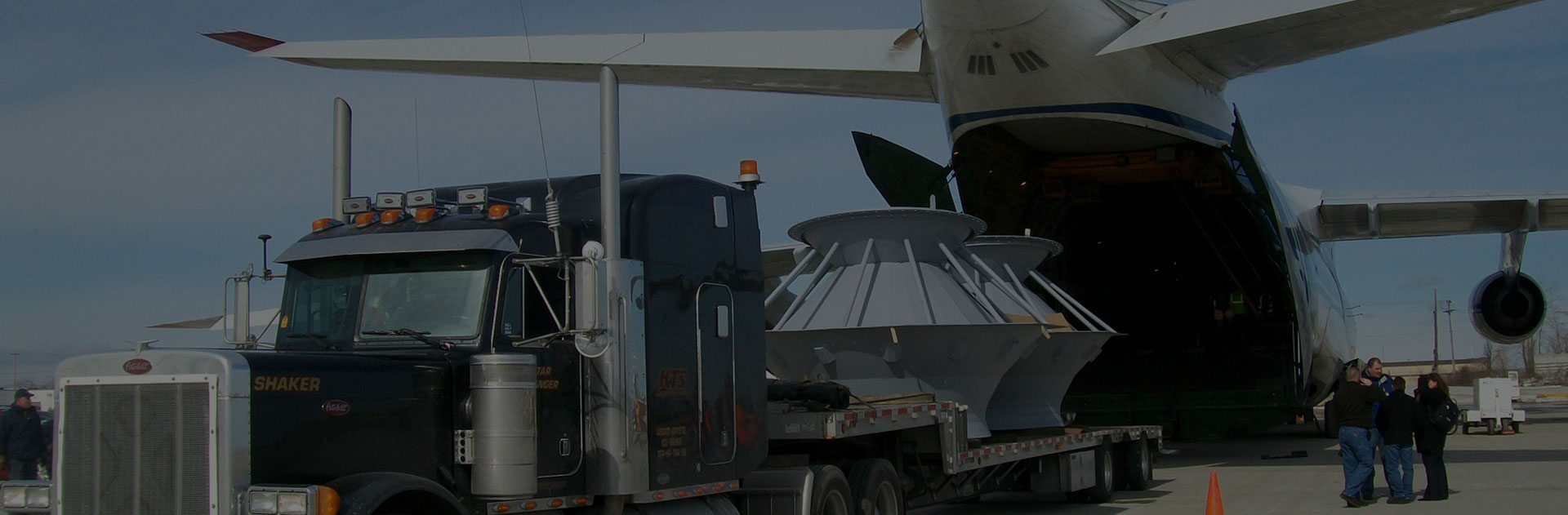 Image of a plane waiting to receive cargo securely positioned on a truck bed.